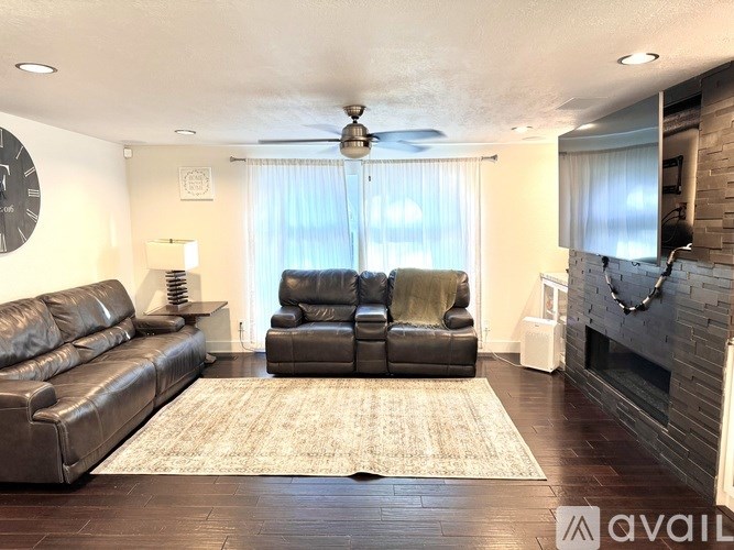 A living room with a black leather couch and a grey sofa.