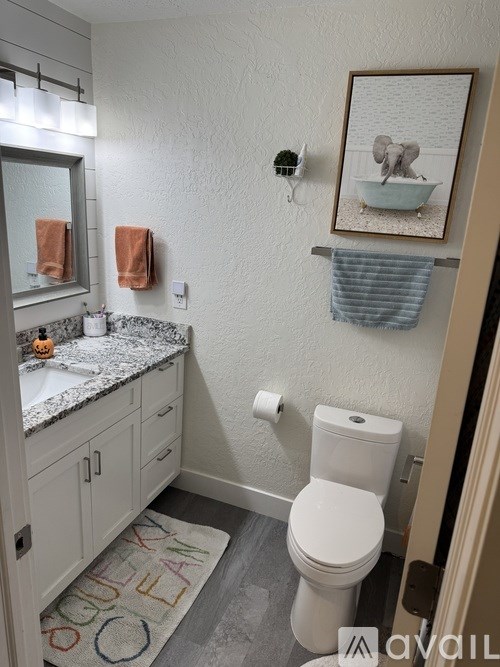 A bathroom with a toilet, sink, and a picture on the wall.