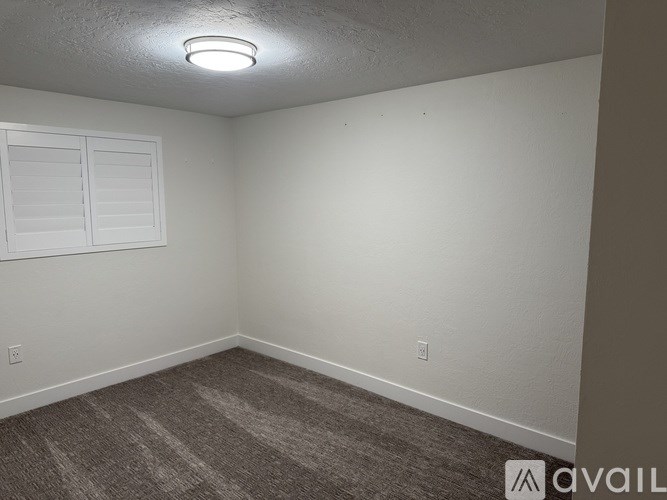 A room with a carpeted floor and a window with closed blinds.