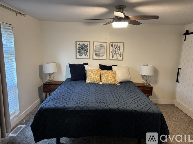 A bedroom with a bed, two lamps, and three framed pictures on the wall.