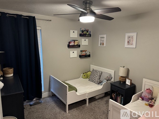 A bedroom with a white bed, a ceiling fan, and a black dresser.