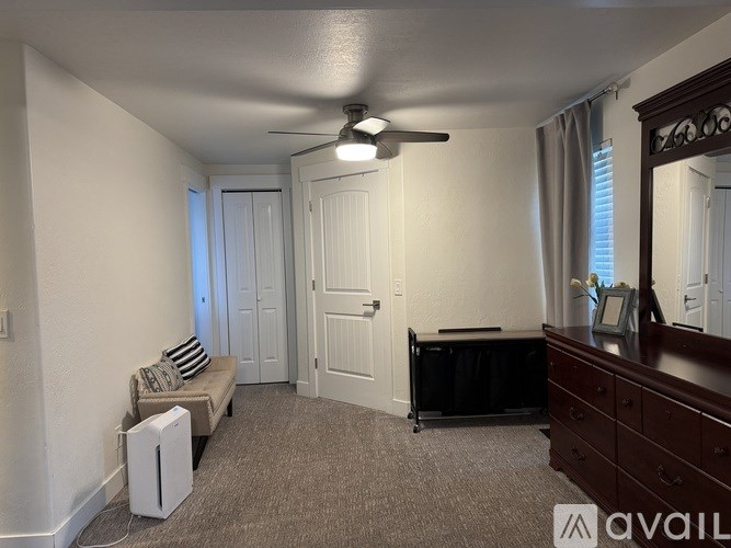 A room with a ceiling fan, a sofa, and a piano.