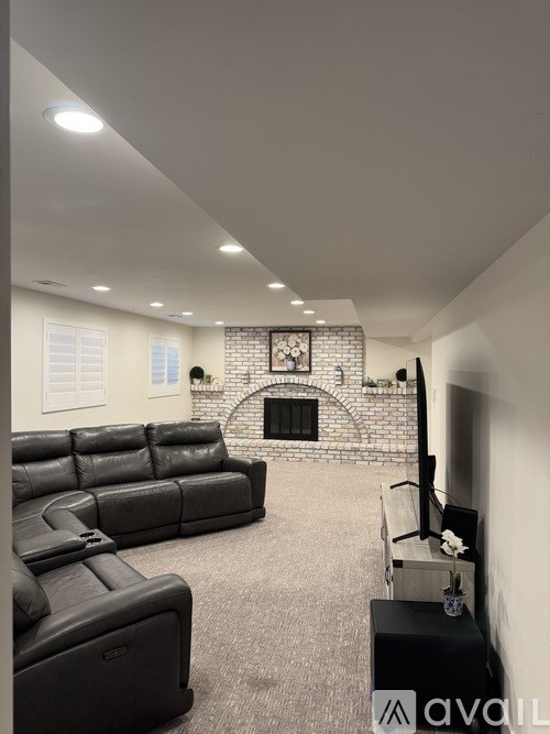 A living room with a black leather couch and a fireplace.