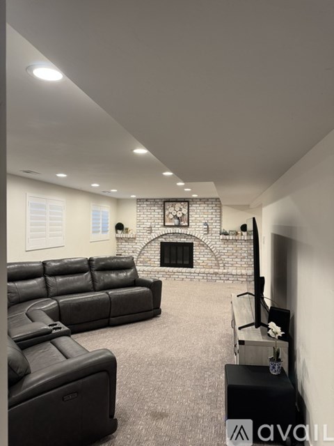 A living room with a black leather couch and a fireplace.