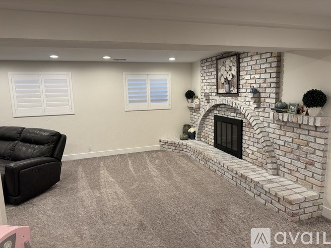A living room with a black leather sofa and a fireplace.