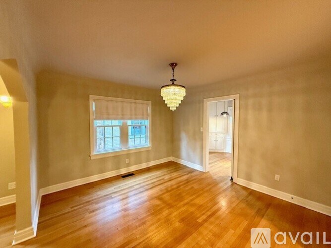 A room with wooden floors and a chandelier hanging from the ceiling.