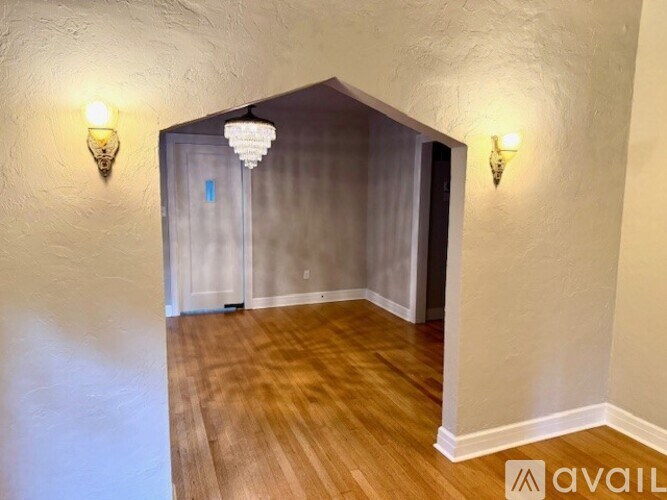 A room with wooden floors and two wall sconces.