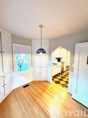 A room with a checkered floor and wooden flooring leading to a hallway.