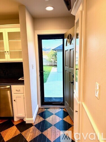 A kitchen with a black fridge and a black and white checkered floor.