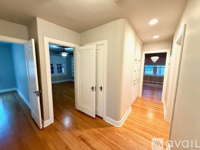 A room with white walls and wooden floors, featuring a white door with a mirror above it.