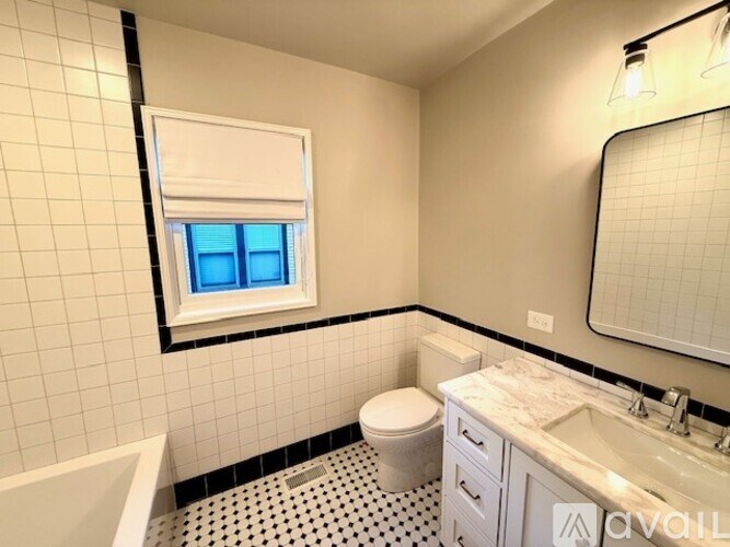 A bathroom with a toilet, sink, and a window with blinds.