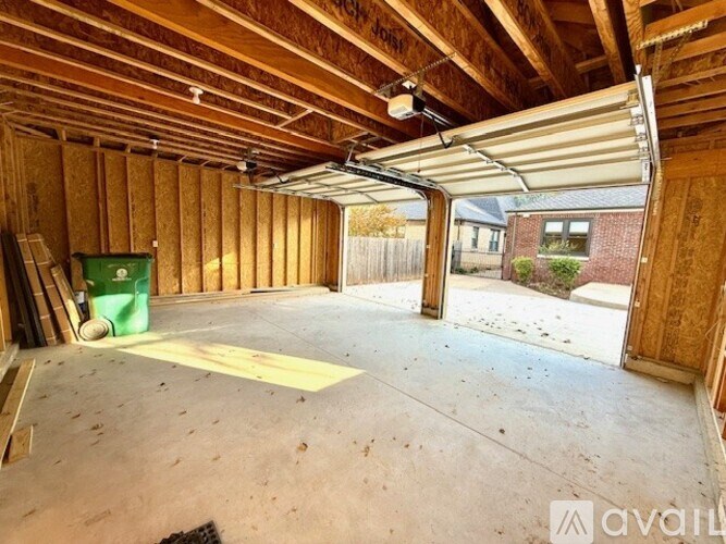 A room under construction with a green trash bin and a white ceiling fan.