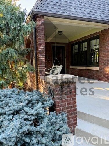 A house with a porch and a tree in front.