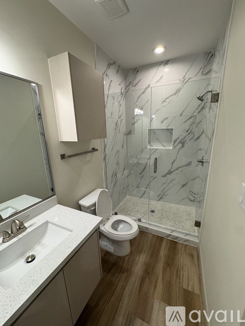 A bathroom with marble wall tiles and a wooden floor.