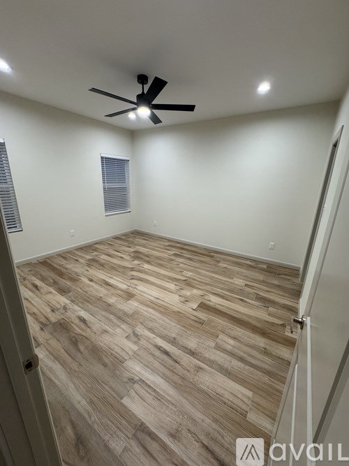A room with a ceiling fan and wooden flooring.