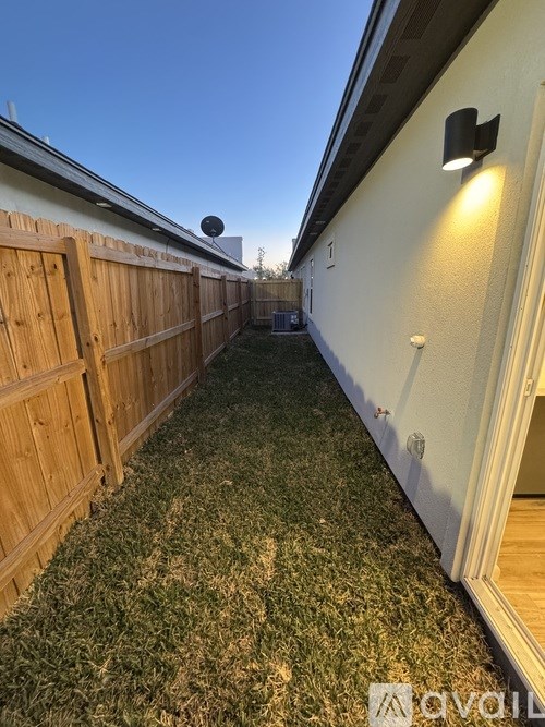 A backyard with a wooden fence and a wall with a light on it.