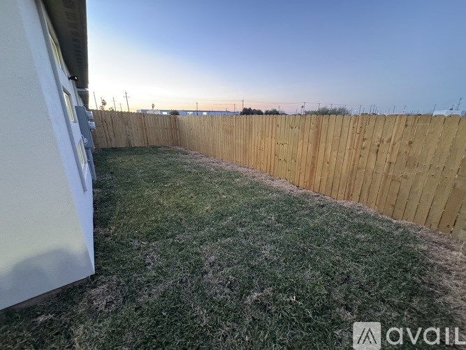 A backyard with a wooden fence and a grassy area.
