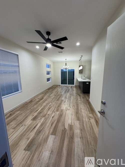 A room with a ceiling fan and wooden flooring.