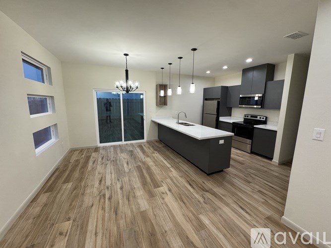 A modern kitchen with wooden flooring and a central island.