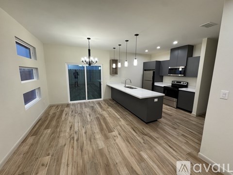 A modern kitchen with wooden flooring and a central island.