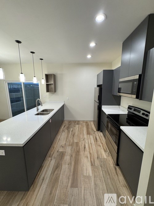 A modern kitchen with wooden floors and black cabinets.
