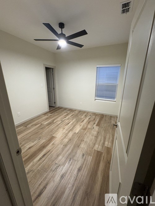 A room with a ceiling fan and wooden flooring.