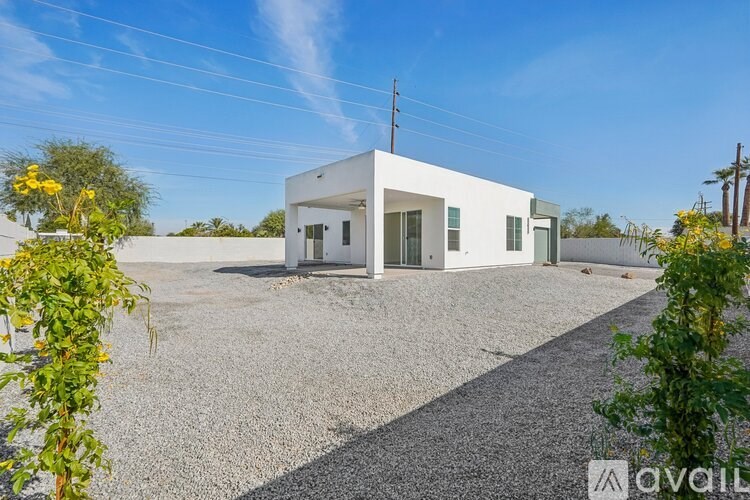 A white building with a gravel driveway in front of it.