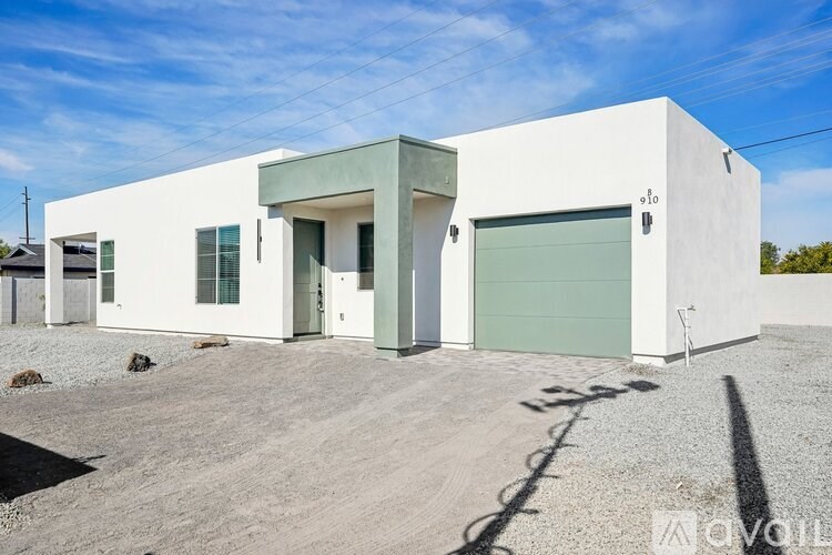 A modern white building with a green door and windows.
