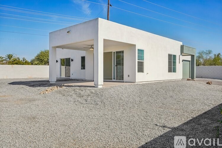 A modern white house with a gravel driveway in front.