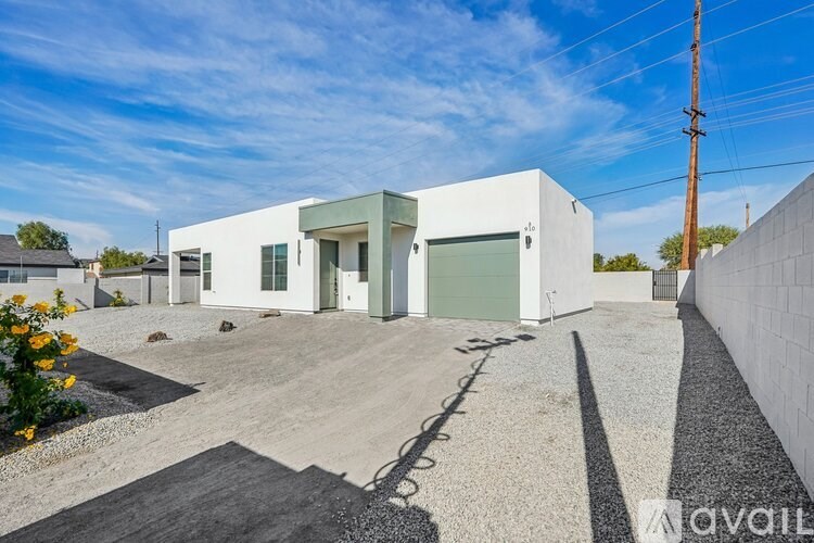 A modern white house with a gravel driveway in front.