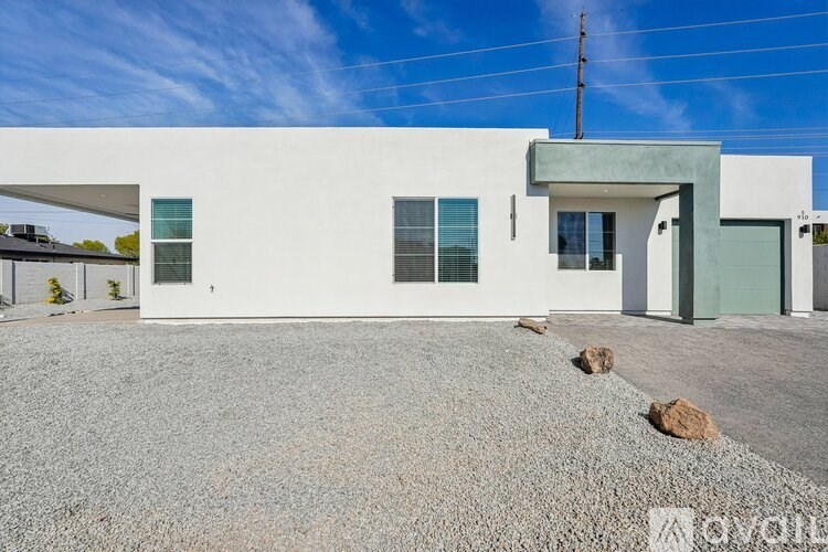 A modern house with a gravel driveway in front.