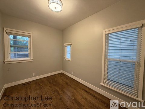 A room with wooden floors and two windows.
