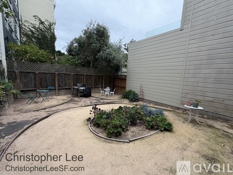 A backyard with a circular garden and a fence.