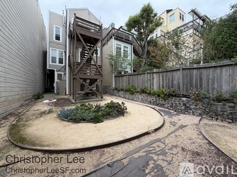 A backyard with a circular sand area and a wooden staircase.