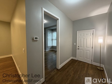 A room with a white door and a lamp on the right side.