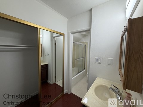 A bathroom with a sink, mirror, and shower.