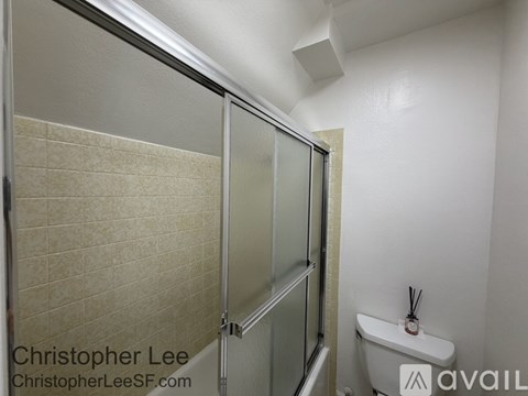 A white bathroom with a glass shower door and a white toilet.