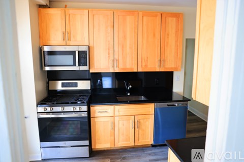 A kitchen with wooden cabinets and black countertops.