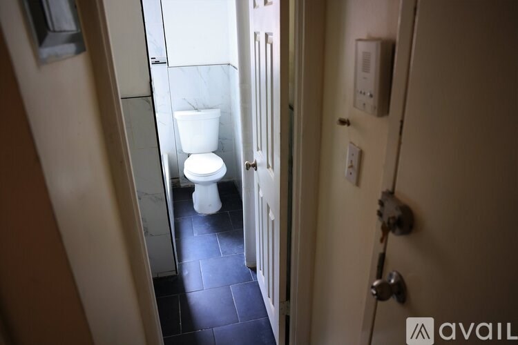 A white toilet is in a narrow hallway.