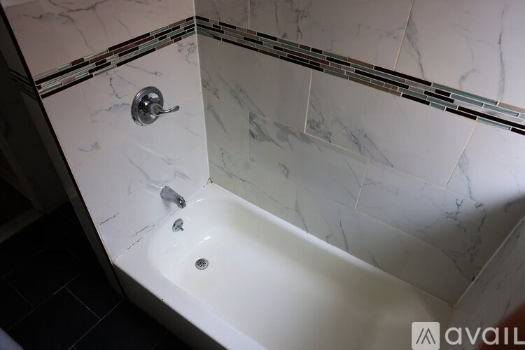 A white bathtub with a silver faucet and a silver shower head.