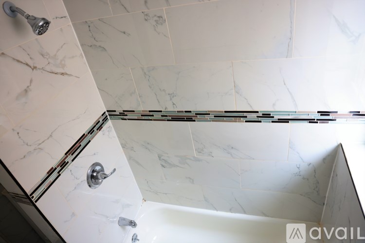 A white bathroom with a marble tile wall and a shower.