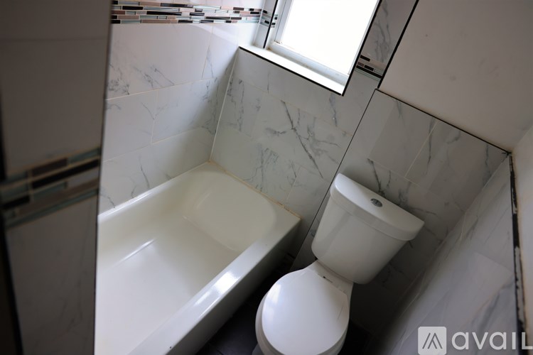 A white toilet sits next to a white bathtub in a bathroom with marble walls.