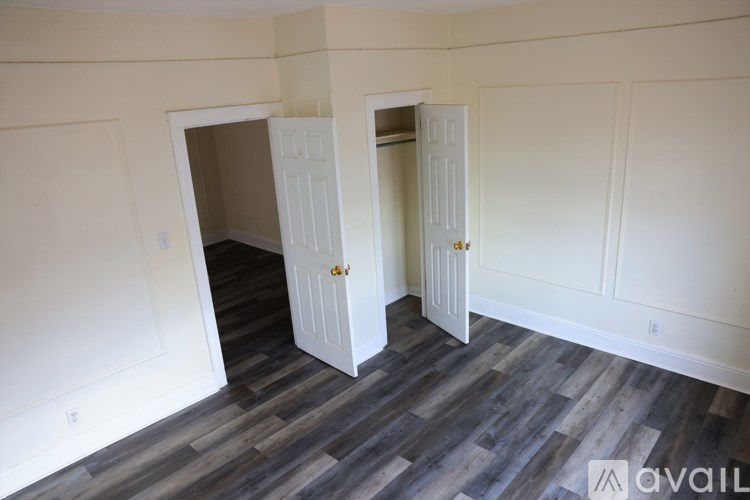 A room with two white doors and wooden flooring.