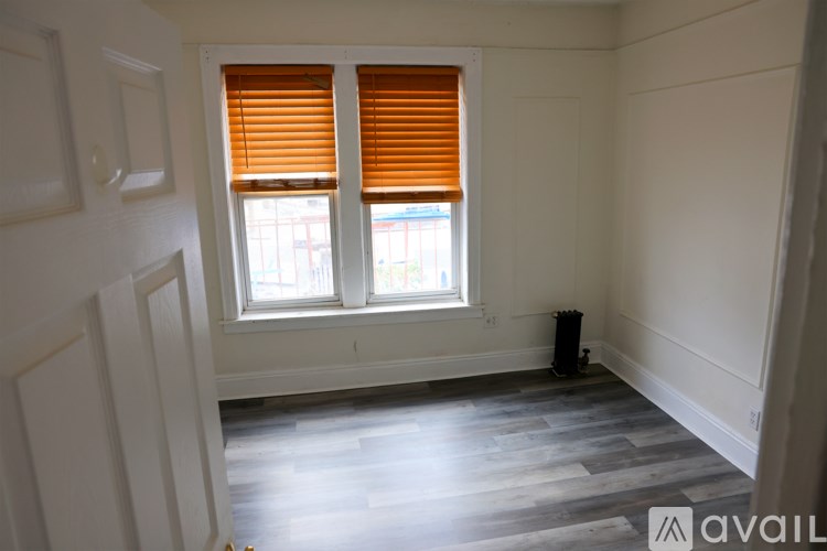 A room with a window covered by orange blinds.