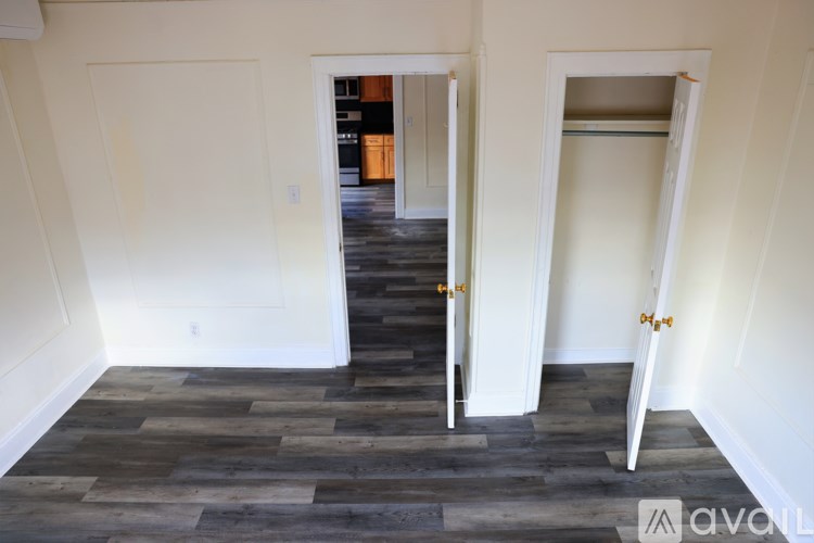 A hallway with a wooden floor and two open doors.