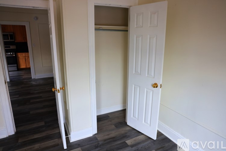 A white door is open to a room with wooden floors.