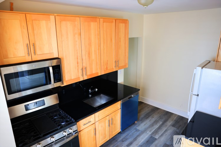 A kitchen with wooden cabinets and black countertops.