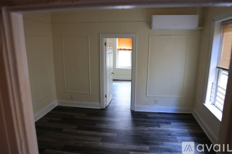A room with wooden floors and a window with blinds.