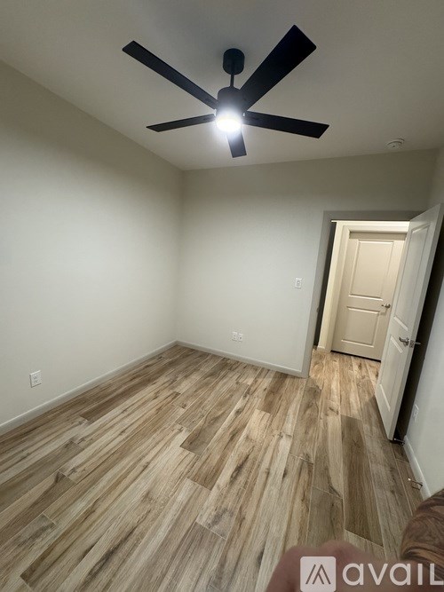 A room with a ceiling fan and wooden flooring.