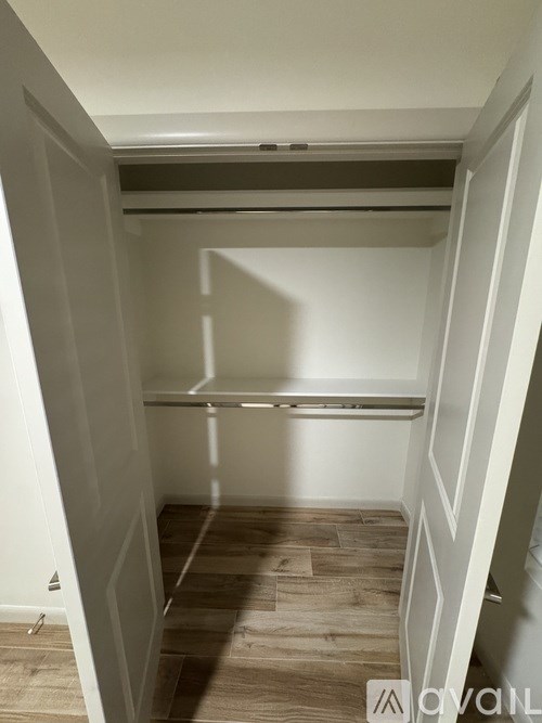 A small, empty room with a wooden floor and white walls.